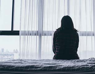 Lonely person sitting on a bed