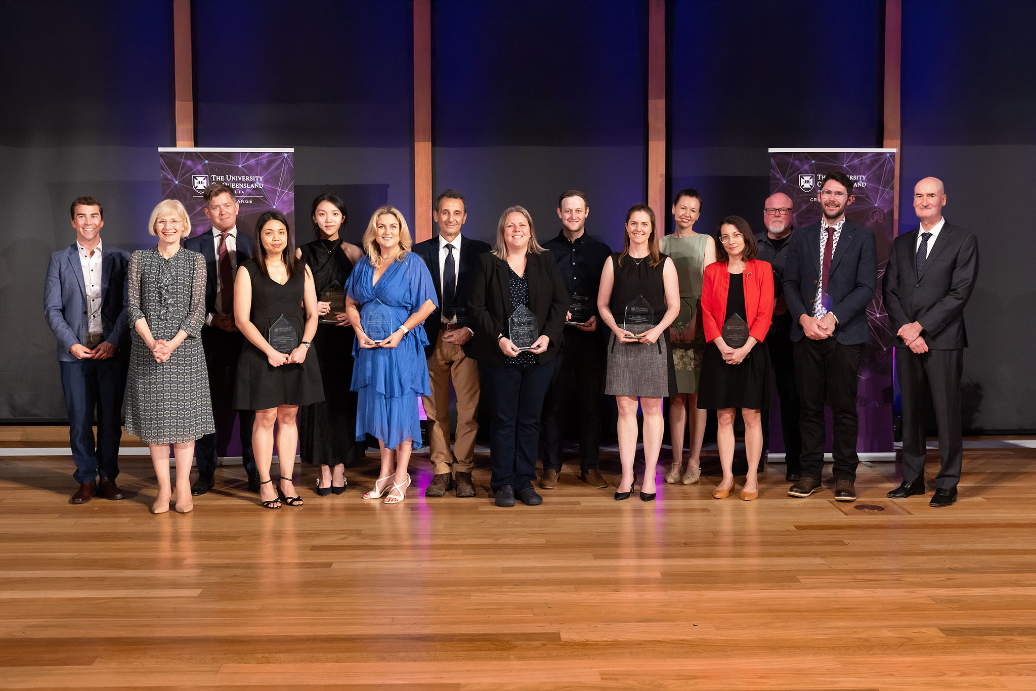 A group of people standing together, some holding awards.