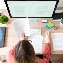 Overhead view of female writer editing paper at computer