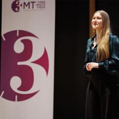 A Phd student on a stage presenting to an audience