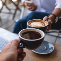 Two people cheering with two cups of coffee